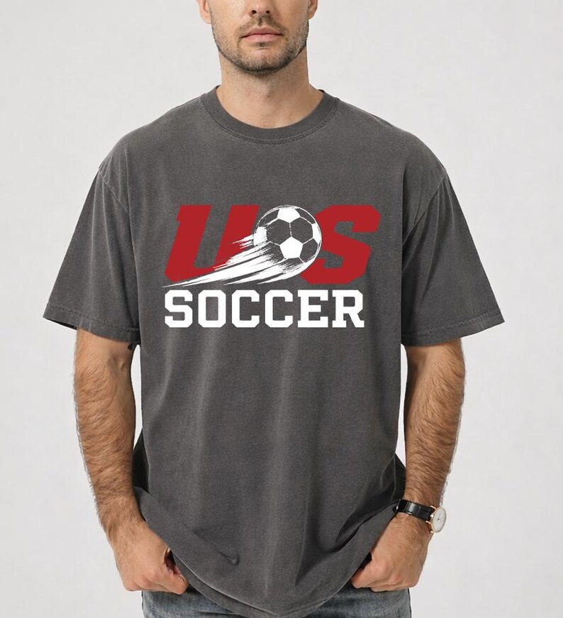 A man wearing a gray t-shirt with the text "U.S. SOCCER" printed on it.