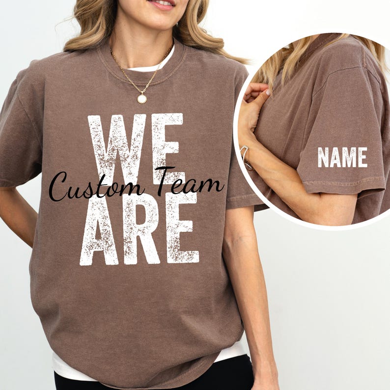 May include: A brown t-shirt with the words "We Are Custom Team" printed in white on the front. The back of the shirt has a blank space for a name.