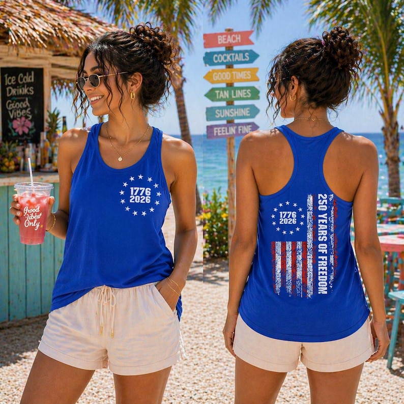 A woman wearing a blue tank top with the text "1776 2026" and "250 YEARS OF FREEDOM" printed on it, standing in front of a beach sign.