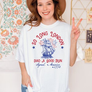 May include: White t-shirt with a blue and red graphic of a ship with fireworks and the text "So Long London" and "Had a Good Run Signed, America *1776".