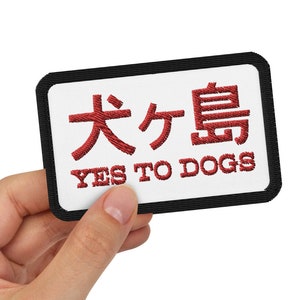 May include: A white patch with black trim and red embroidery. The patch says "Yes to Dogs" and has Japanese characters in red.