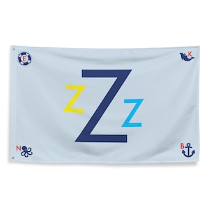 May include: Light blue flag with a navy blue 'Z' and two smaller 'Z's in yellow and blue. Nautical themed with a life preserver, octopus, whale, and anchor in the corners. A fun, decorative item.
