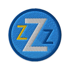 May include: A blue and white embroidered patch with the letter "Z" in a stylized font. The letter "Z" is outlined in yellow.