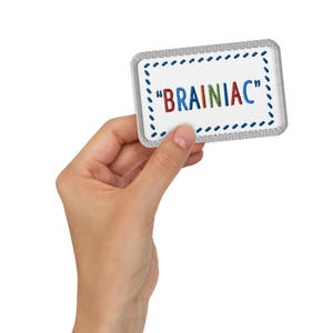 May include: A white card with a blue, gray, and white stitched border. The card has the text "BRAINIAC" in colorful letters.
