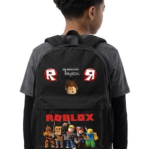 May include: A black backpack featuring the Roblox logo in red text at the bottom, accompanied by a graphic of five blocky characters. The top section displays two red circular logos with a white R, a central character head, and the text Track by T-Rack.