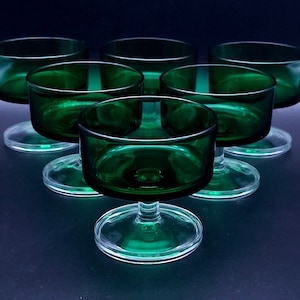 Op de afbeelding: Set van zes groene glazen dessertschaaltjes met heldere glazen stelen. De schaaltjes zijn rond en hebben een lichte rand.