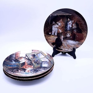 May include: Set of three ceramic plates featuring a vintage illustration of a group of kittens gathered around a bowl of milk. The plates are decorated with a brown, white, and black color scheme.