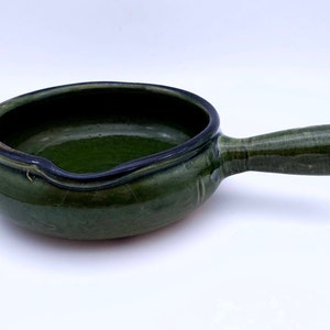 Puede incluir: Un plato de servir de cerámica verde con un asa. El plato tiene un esmalte verde oscuro con un borde negro.