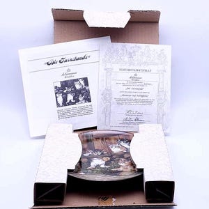 May include: A ceramic plate with a picture of kittens playing in a barn. The plate is in a cardboard box with a certificate of authenticity. The certificate is in German and says "Echtheitszertifikat" which means "Certificate of Authenticity".