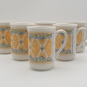 May include: Set of six white ceramic mugs with a yellow, blue, and green geometric pattern. The mugs have a handle on one side.