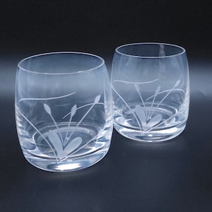 Peut inclure: Deux verres &agrave; boire en verre transparent avec des motifs de fleurs stylis&eacute;es grav&eacute;s. Les verres sont ronds et ont une base large.