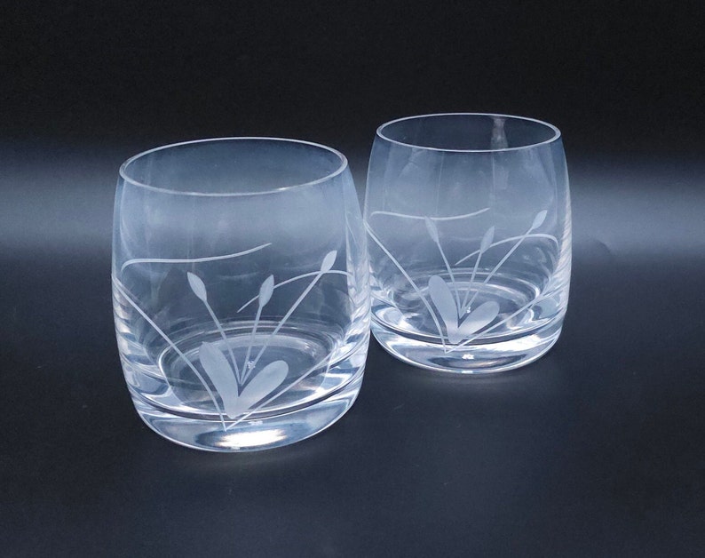 Peut inclure: Deux verres &agrave; boire en verre transparent avec des motifs de fleurs stylis&eacute;es grav&eacute;s. Les verres sont ronds et ont une base large.