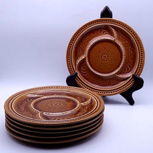 May include: Set of six brown ceramic divided serving plates with a decorative floral design. Each plate has three sections and a central dip.