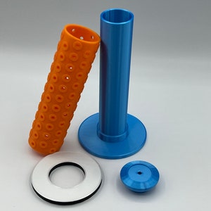 May include: A set of 3D printed parts for a 3D printer. The set includes a blue tube with a base, a white ring with a black inner ring, and a blue cap. The tube has a textured surface with small holes.