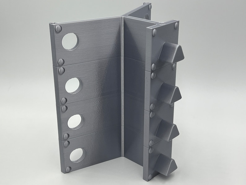 May include: A gray metal stand with four triangular spikes on one side and five round holes on the other side.