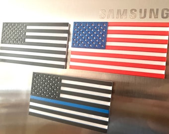May include: Three American flag magnets, one with a thin blue line, one with red and white stripes, and one with black and white stripes.