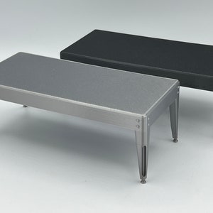 May include: Two small, rectangular tables with a textured surface. One table is silver and the other is black.