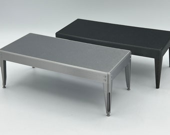 May include: Two small, rectangular tables with a textured surface. One table is silver and the other is black.