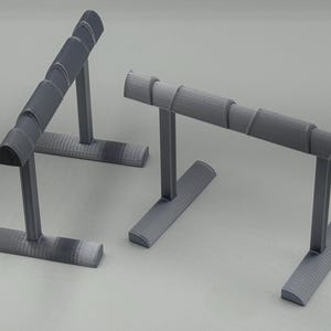 May include: Two gray jewelry display stands. Each stand has a rectangular base, a vertical support, and a curved top designed to hold jewelry. The stands are made of a textured material and are set against a neutral background.