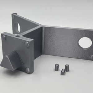 May include: A gray 3D printed plastic part with a triangular knob and four small cylindrical pieces. The part has a Y-shaped design with a flat surface on one side.
