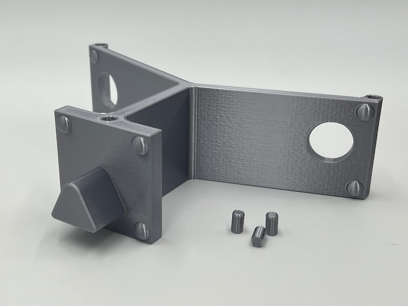 May include: A gray 3D printed plastic part with a triangular knob and four small cylindrical pieces. The part has a Y-shaped design with a flat surface on one side.