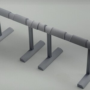 May include: A gray jewelry display stand with a horizontal bar supported by vertical posts and a base. The bar has a series of cylindrical sections. The stand is designed to hold bracelets or necklaces.