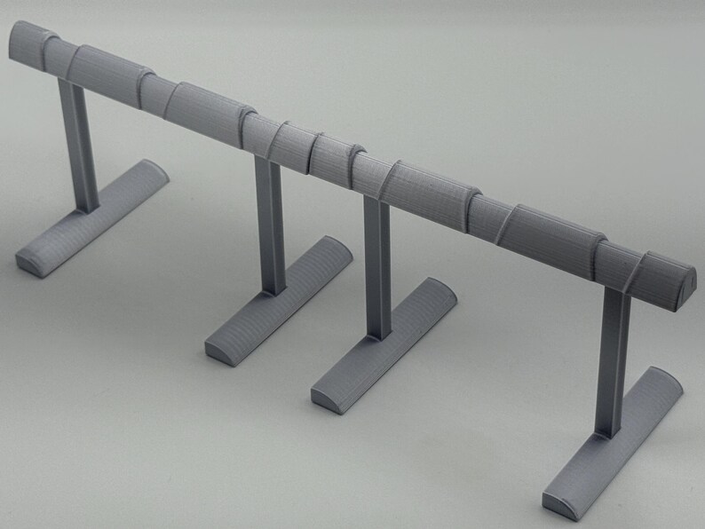 May include: A gray jewelry display stand with a horizontal bar supported by vertical posts and a base. The bar has a series of cylindrical sections. The stand is designed to hold bracelets or necklaces.