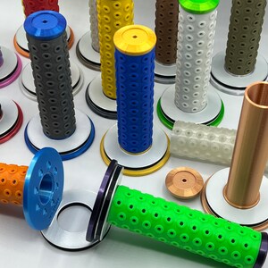 May include: Assortment of colorful motorcycle grips with different patterns and textures. The grips are displayed on white bases with black trim.