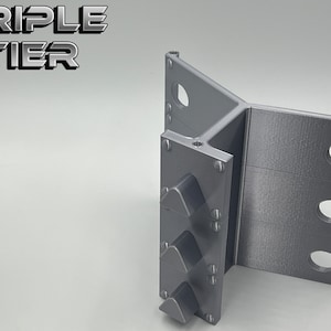 May include: A gray, three-tiered, 3D printed stand with a triangular shape. The stand has three slots on each side for holding items.