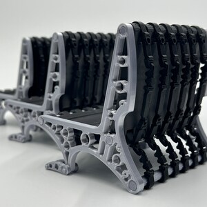 May include: A set of two gray plastic benches with black rubber seats. The benches are made of a lattice-like design and have a modern, minimalist aesthetic.