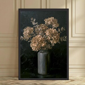 May include: A framed artwork featuring a still life of dried hydrangeas in a gray vase against a dark textured background. The flowers are a mix of beige and tan, with hints of green leaves. The vase is cylindrical and sits on a dark surface.