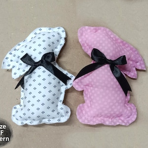 May include: Two bunny-shaped fabric ornaments. One is white with a black floral pattern, the other is pink with white polka dots. Both have black ribbon bows. The text "3 Size PDF Pattern" is in the lower left corner.
