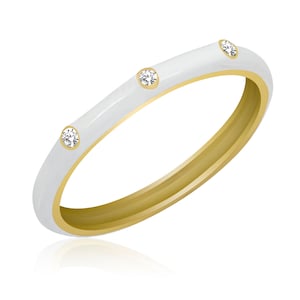 May include: A white enamel ring with three small diamonds set in gold. The ring is thin and delicate.
