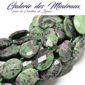 Puede incluir: Una hebra de cuentas ovaladas de piedra preciosa verde, negra y rosa. Las cuentas están enhebradas en un hilo verde.