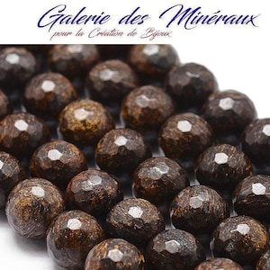 Peut inclure: Un brin de perles de pierres précieuses facettées brun foncé. Les perles sont rondes et ont une texture légèrement rugueuse. Les perles sont disposées en rangée et sont proches les unes des autres.