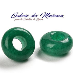 Könnte beinhalten: Zwei grüne Jade-Donut-Perlen mit einem Loch in der Mitte. Die Perlen sind glatt und poliert.