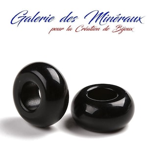 Puede incluir: Dos cuentas negras en forma de rosquilla con un agujero en el centro. Las cuentas son lisas y brillantes.