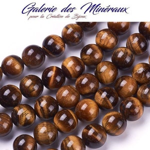 Puede incluir: Una hebra de cuentas redondas de ojo de tigre marrón. Las cuentas tienen un brillo dorado y una calidad ligeramente iridiscente.