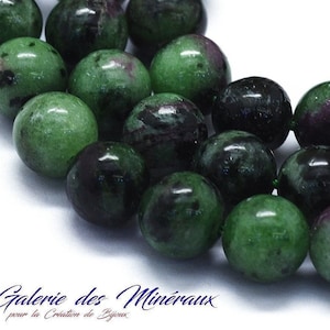 Peut inclure: Un brin de perles de pierres précieuses vertes, noires et violettes. Les perles sont rondes et ont une finition lisse et polie.