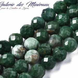 Peut inclure: Un brin de perles de pierres précieuses vertes de forme arrondie facettées. Les perles sont disposées en ligne, le haut du brin étant légèrement incliné. Les perles ont une couleur verte marbrée avec des inclusions vert foncé et brunes.