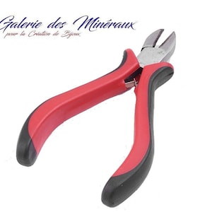 Puede incluir: Cortadores de alambre con mangos rojos y negros y una cuchilla de metal plateado. Los cortadores se utilizan para la fabricación de joyas.