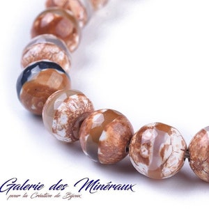 May include: A strand of brown, white and black agate beads. The beads are round and have a polished finish. The beads are strung on a wire and are ready to be used for jewellery making.