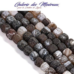 Peut inclure: Un collier de perles de forme carrée présentant une palette de couleurs brun foncé et noir avec des motifs de craquelures blanches sur la surface. Les perles ont une texture lisse et polie, disposées en une formation dense et multi-rangs.
