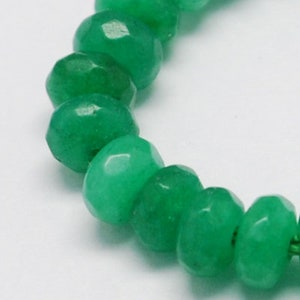 May include: A strand of green jade beads, each bead is faceted and has a rounded shape.