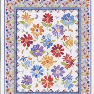 Può includere: Una trapunta rettangolare intitolata Blooming Day & Night caratterizzata da un pannello centrale bianco con motivi floreali multicolori sparsi in rosso, arancione, viola e blu. La trapunta ha un bordo decorativo con piccoli fiori.