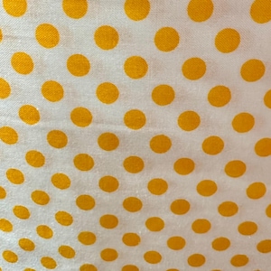 May include: White fabric with a repeating pattern of yellow polka dots. The dots are arranged in a diagonal pattern.