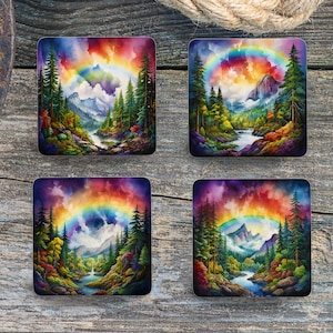 Puede incluir: Cuatro posavasos cuadrados con una pintura de acuarela de un arcoíris sobre una escena de bosque. El arcoíris es multicolor y el bosque es verde con un río azul que fluye a través de él. El fondo es un cielo nublado con una cordillera en la distancia.