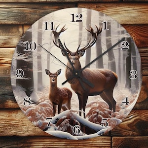 May include: Round wall clock featuring a majestic stag and a fawn in a winter forest scene. The clock face displays large black numerals and black clock hands. The clock is mounted on a wooden background.