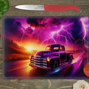 May include: Purple vintage pickup truck driving on a road with a stormy sky and lightning in the background. The truck is driving towards a sunset.
