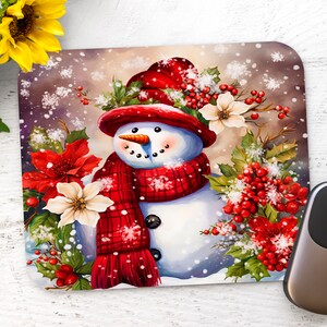 May include: A festive mousepad featuring a snowman with a red hat and scarf surrounded by holly, poinsettia, and white flowers. The background is a snowy winter scene.